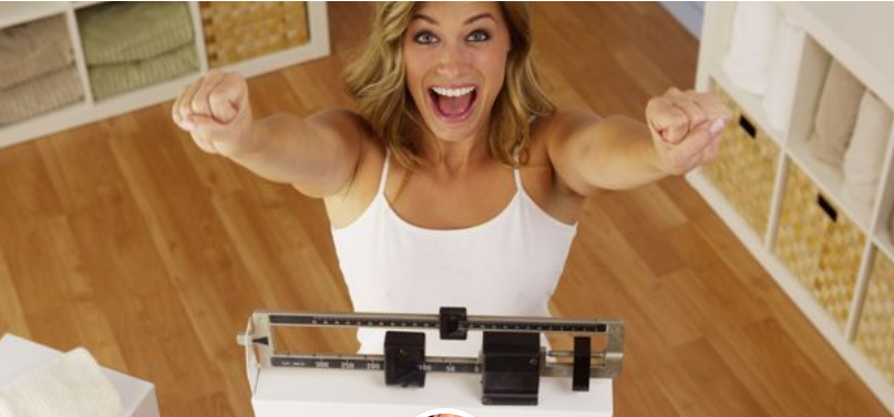 Woman smiling while standing on scale.